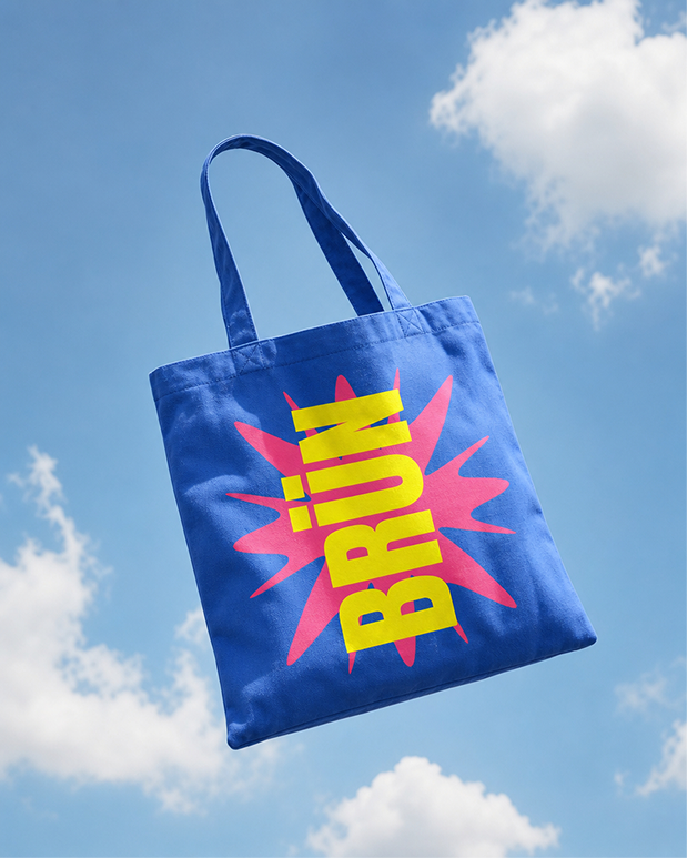 Blue BRÜN canvas tote bag floating against a blue sky